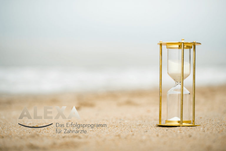 Eine goldene Sanduhr auf Wüstensand.